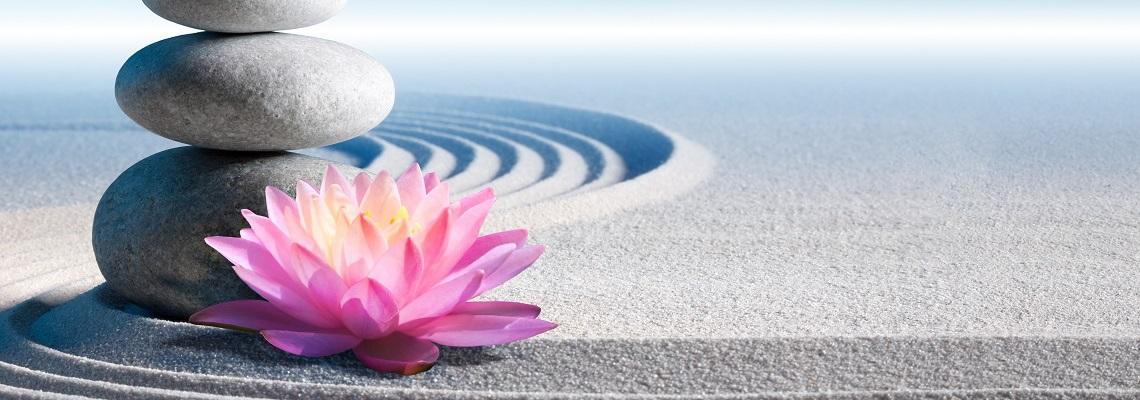 Zen stones with pink flower on rippling sand
