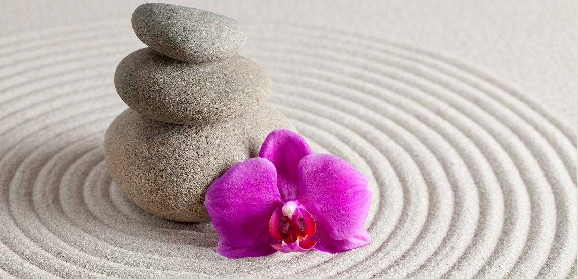 Zen stones with orchid flower on rippling sand
