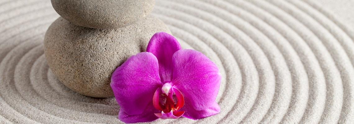 Zen stones with purple orchid flower on rippling sand